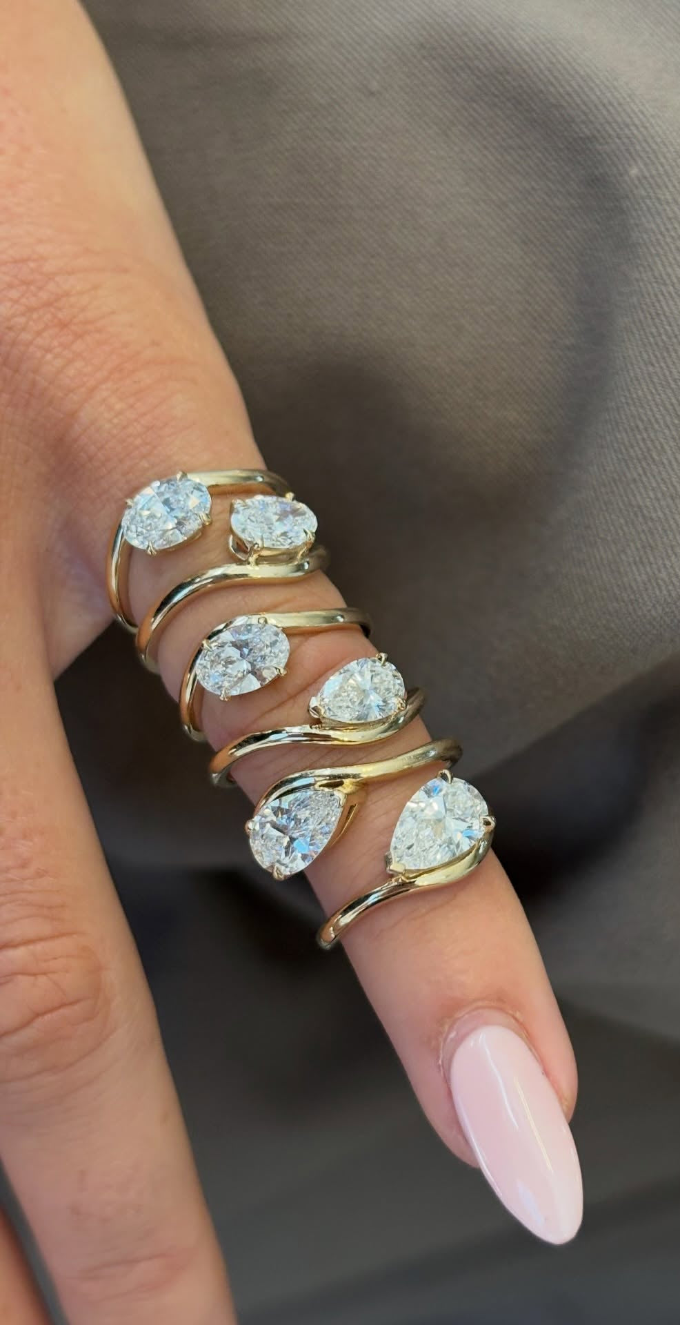 Gold ring with diamond stones on a finger against a neutral background